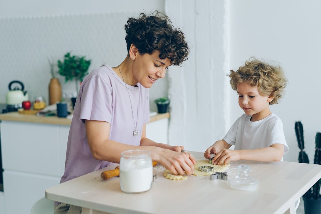 A parent and their son baking together at the kitchen table